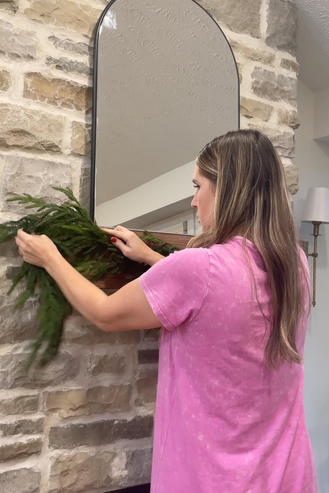 Hanging realistic pine garland on a fireplace mantel.